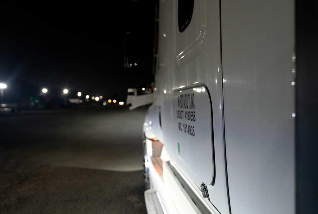 Autonomous truck driving towards Dallas on the road at night.