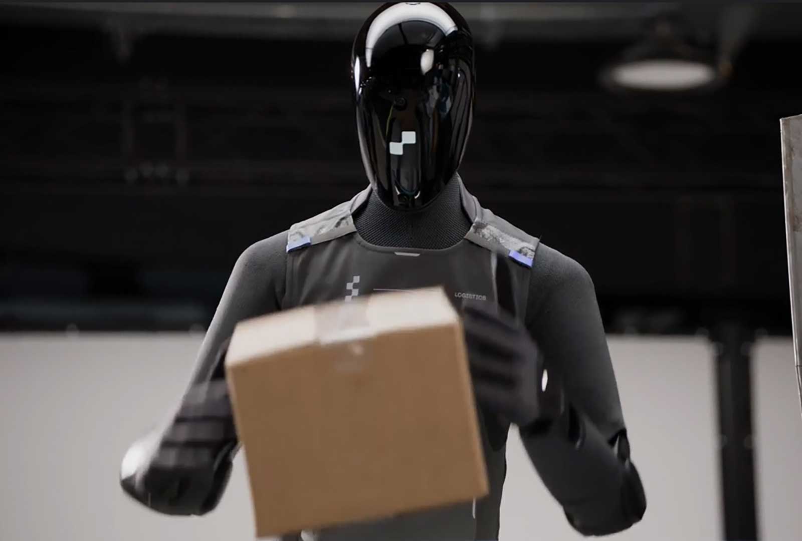 Autonomous delivery robot handling a package in a warehouse setting.