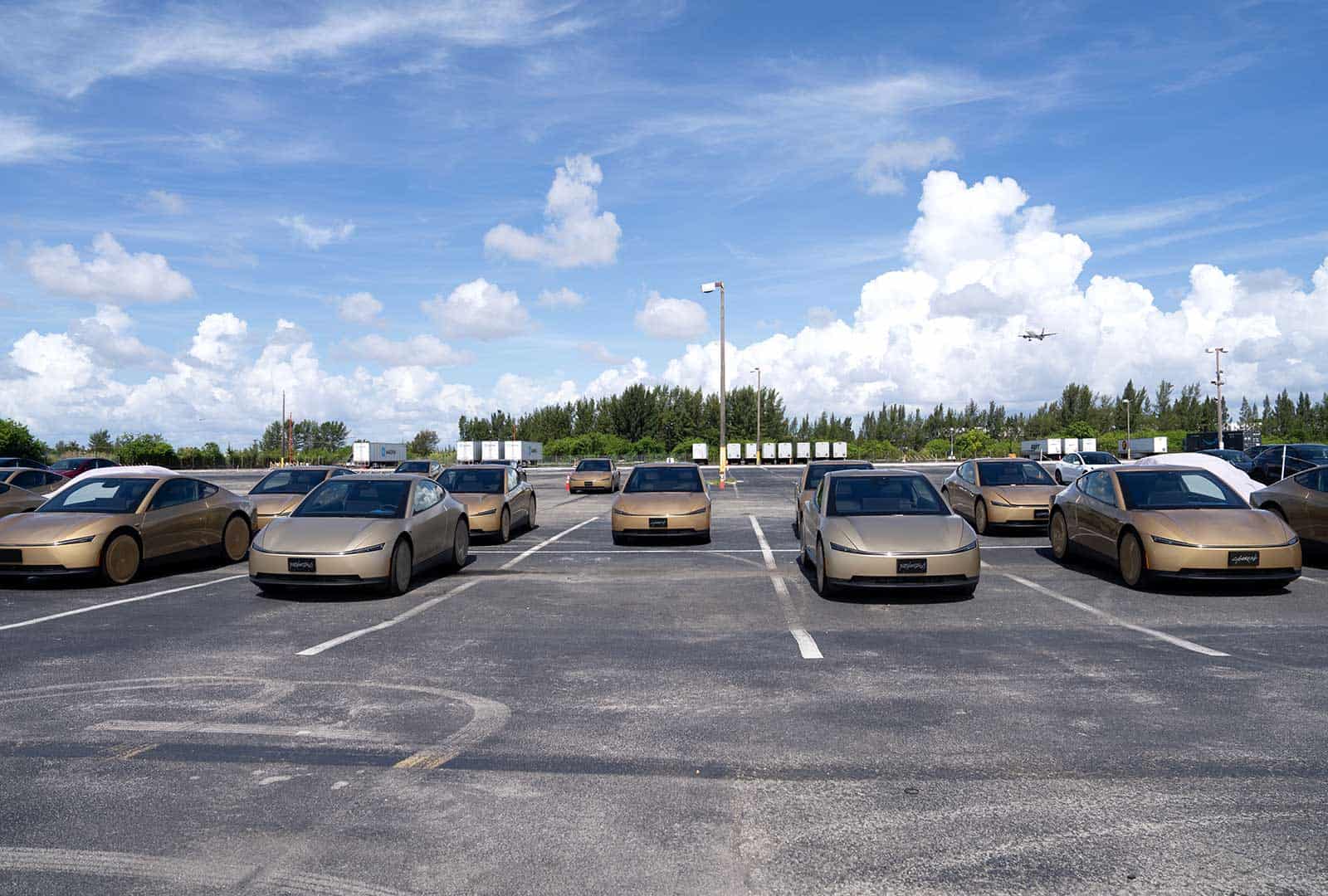 Multiple autonomous cars parked in a lot under a blue sky.