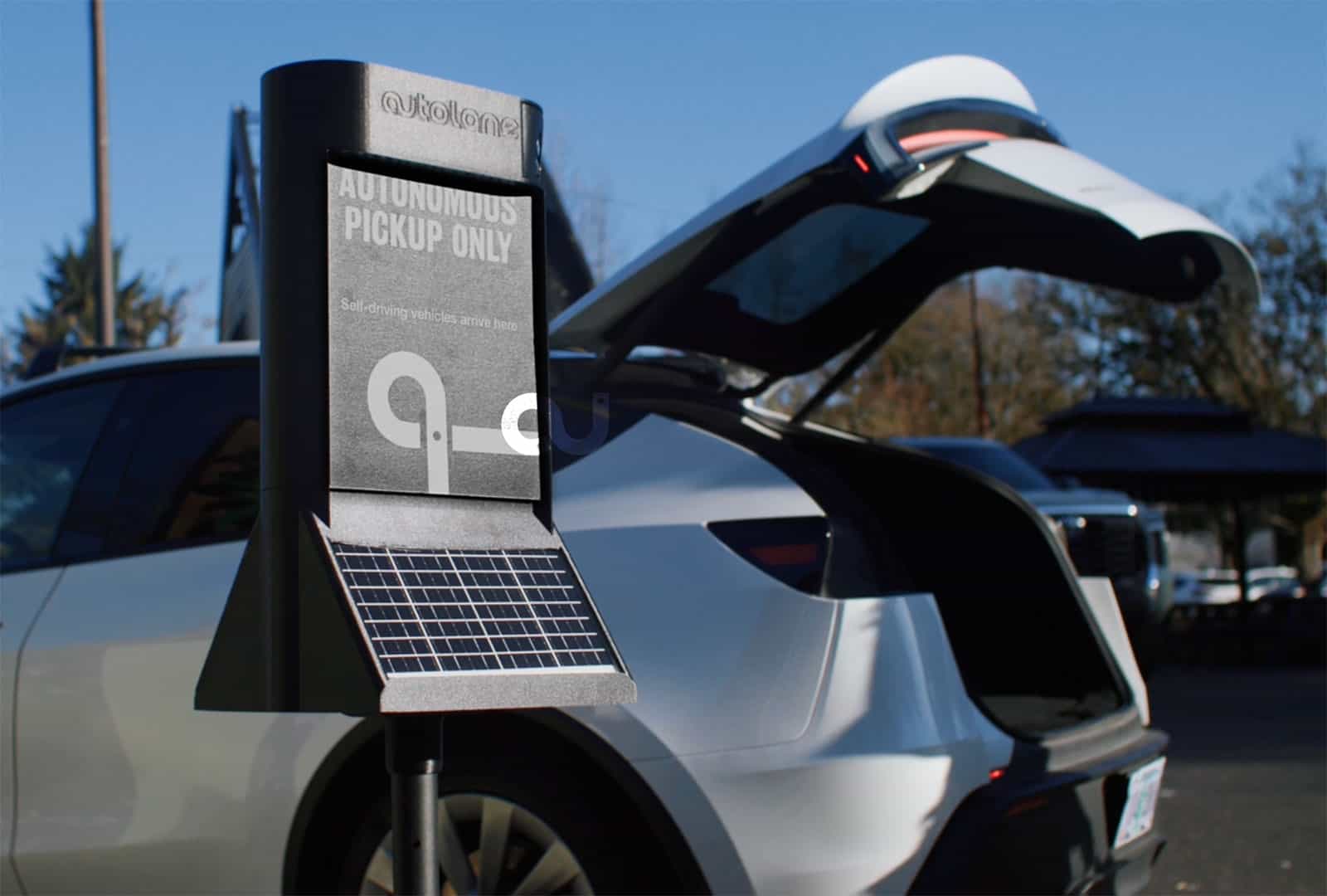 Autonomous vehicle charging station with solar panel and pickup area.