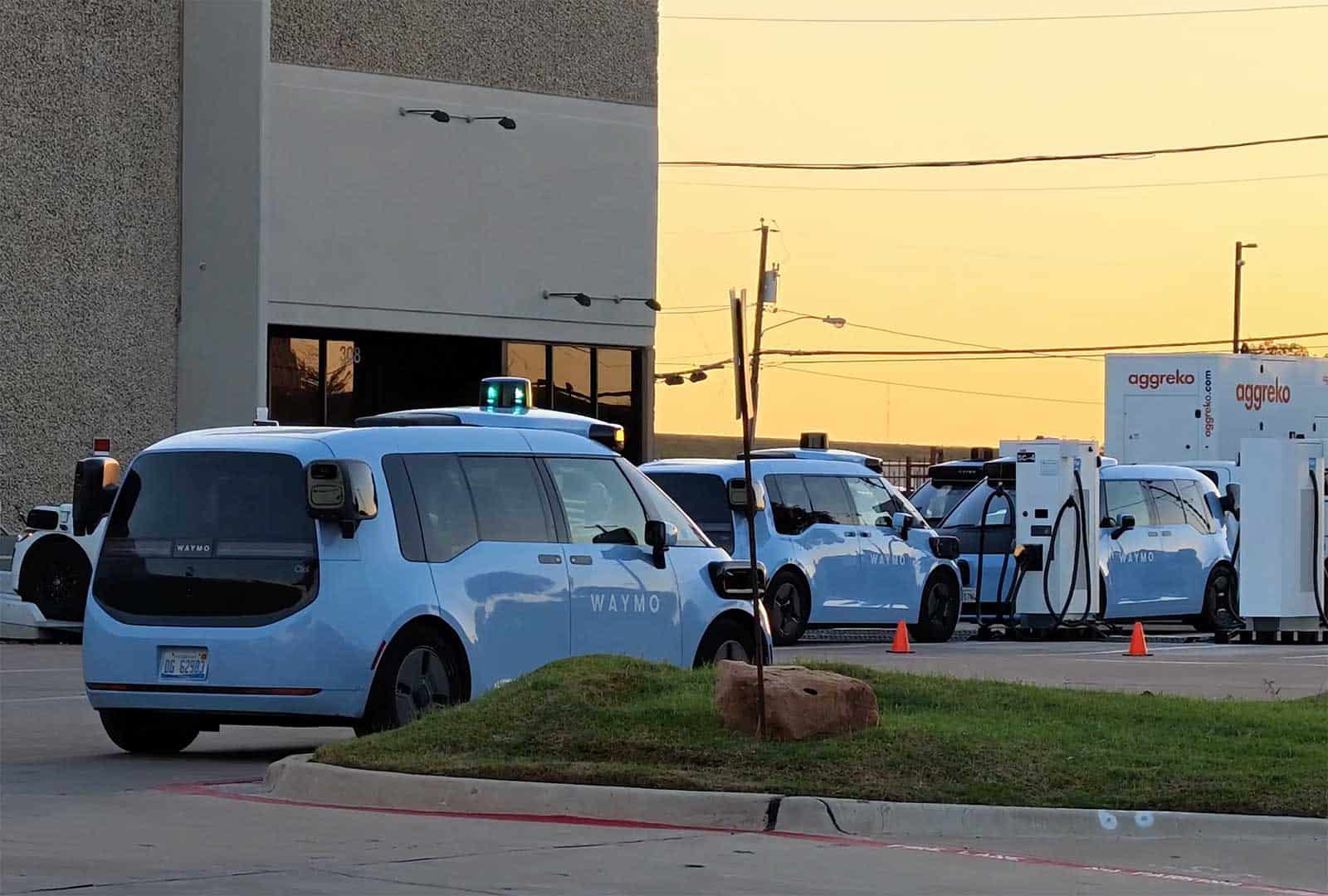 Waymo self-driving cars at Dallas depot during sunset.